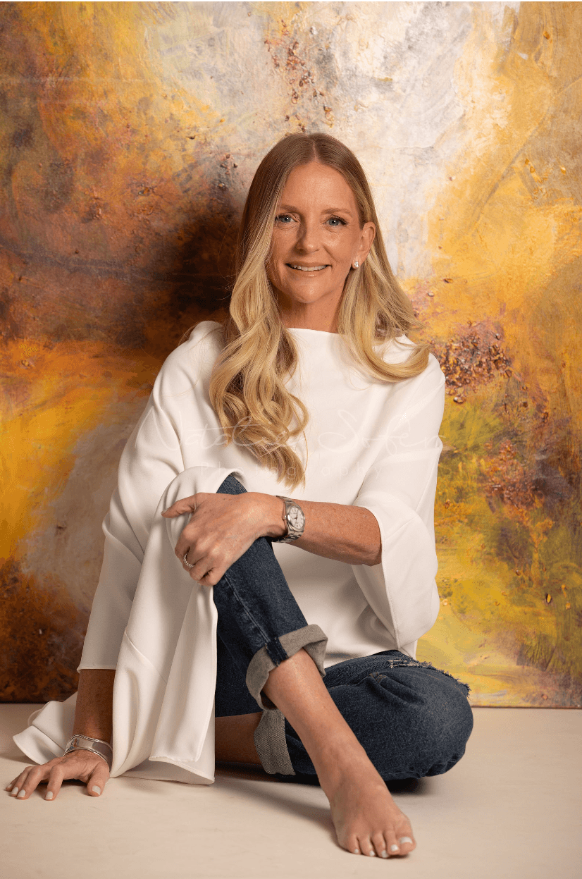 Bernice Abadi seated in front of one of her paintings